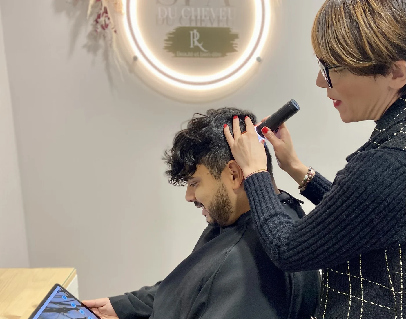 Lucia observe le cuir chevelu d’un client avec une micro-caméra