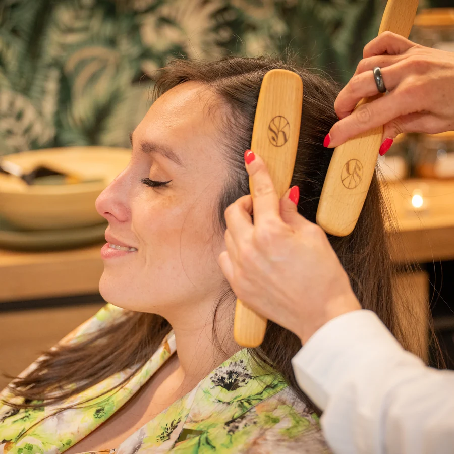 Geste de massage avec des brosses en bois, photographié au salon